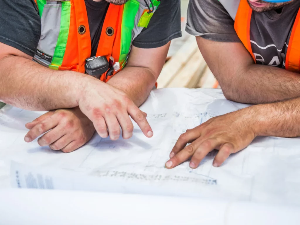 Ingénieurs en gilet de sécurité travaillant sur des plans techniques